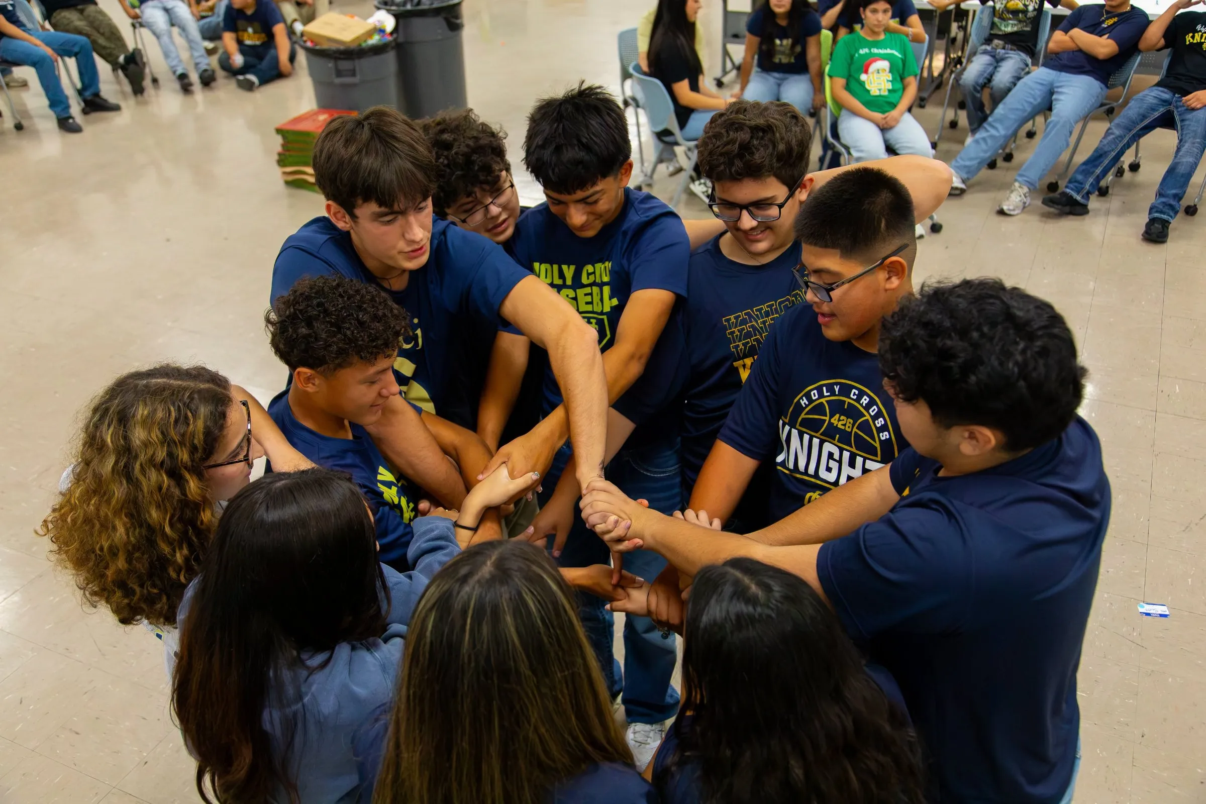 A group of Holy Cross students in a huddle, hands joined