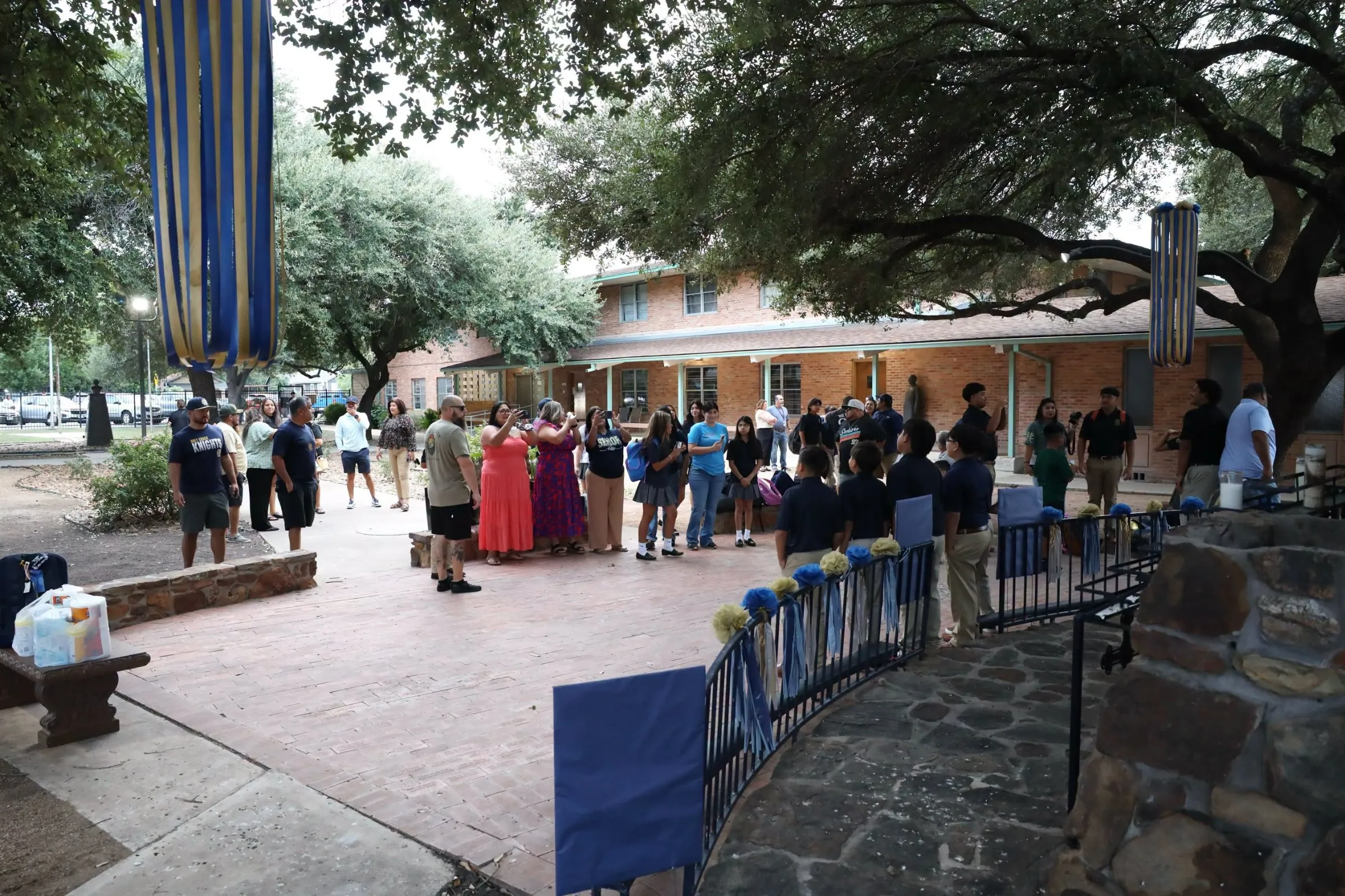 Holy Cross families and students gathered in the courtyard under the oak trees