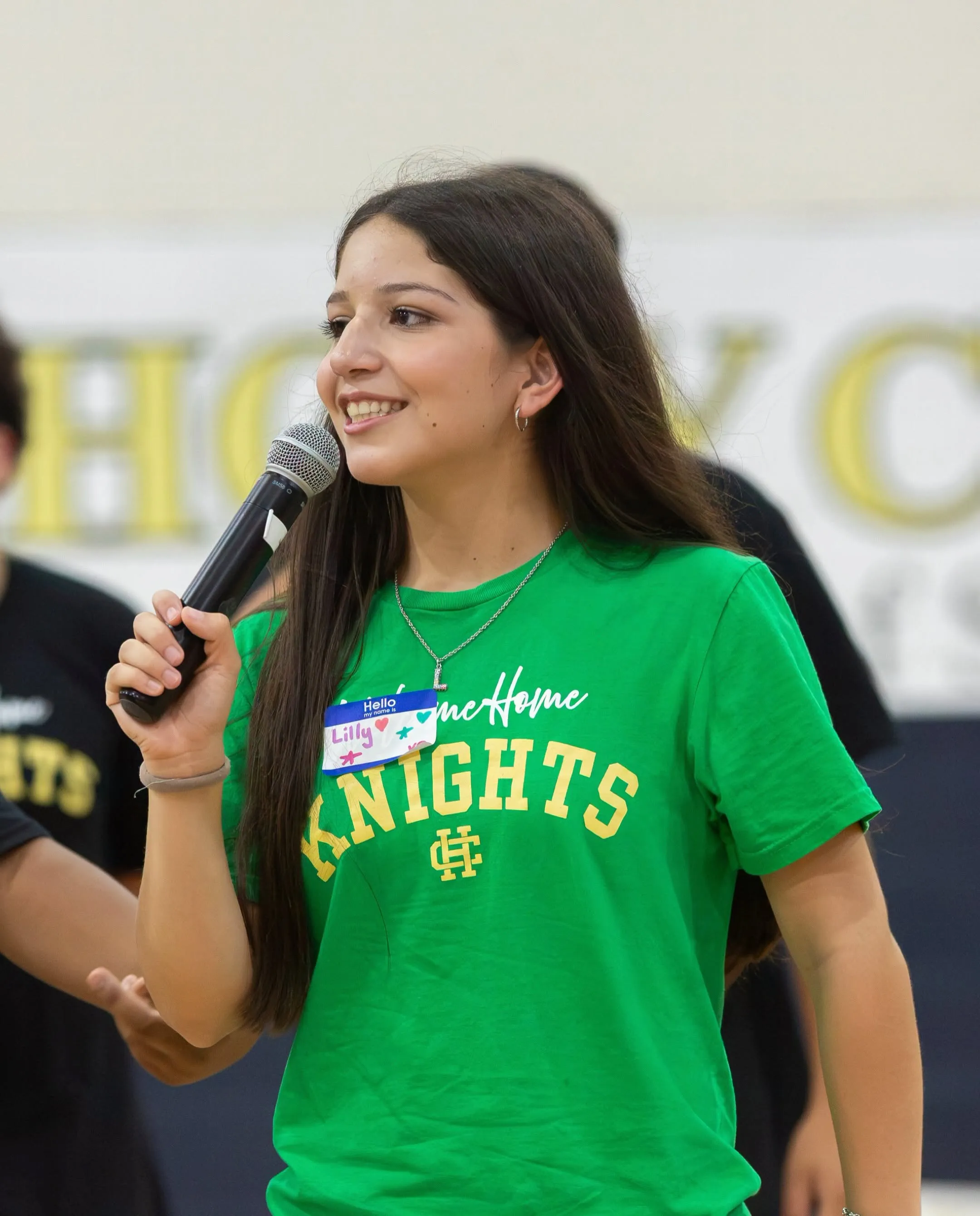 A student speaking into a microphone at a school assembly